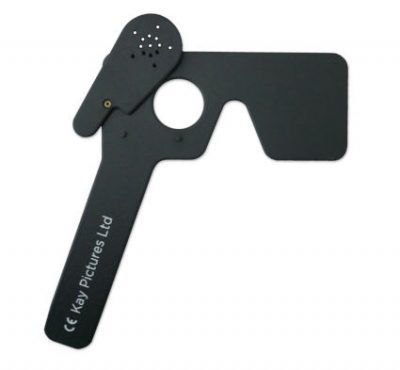 The image is of a black plastic occluder, a tool commonly used in eye examinations. It has a handle on the left side, labeled "Kay Pictures Ltd," and a flat rectangular part to the right used to cover one eye during vision tests. There is also a smaller circular section with multiple pinholes that can be rotated into position for pinhole testing. The occluder is designed for use by optometrists or ophthalmologists to assess and measure visual acuity.